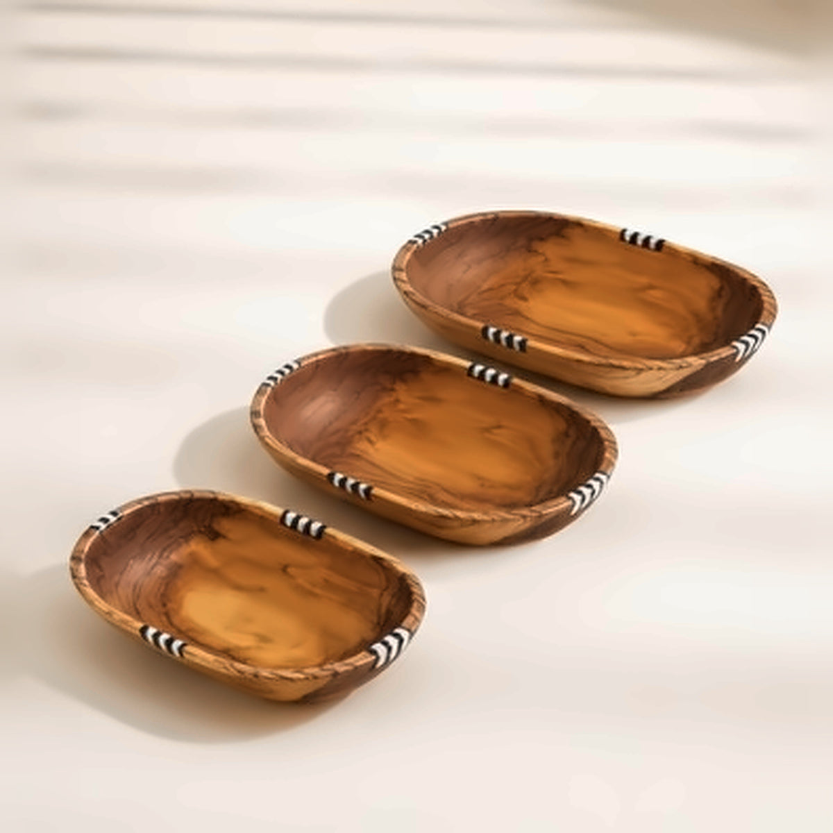 The three olive wood bowls separated and arranged in a row, showing the graduated sizes of the set