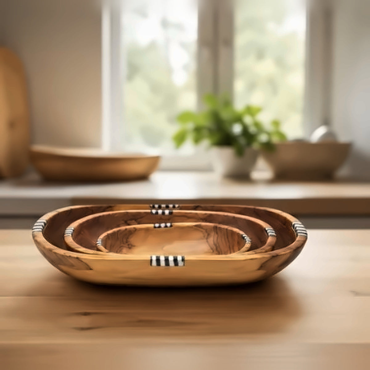 Olive wood nesting bowls with bone inlay on a wooden kitchen counter in front of a window