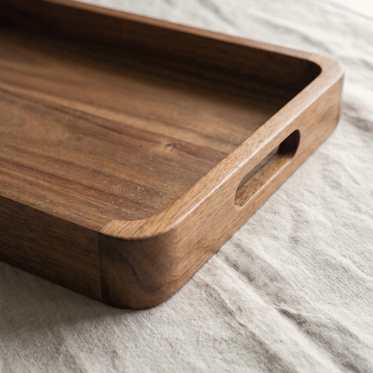 Detail of the raised edge and cut-out handle of the acacia serving tray