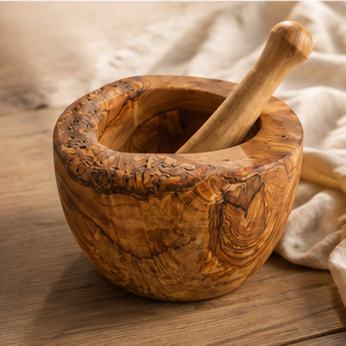 Olive wood mortar and pestle on a wooden table beside a linen cloth