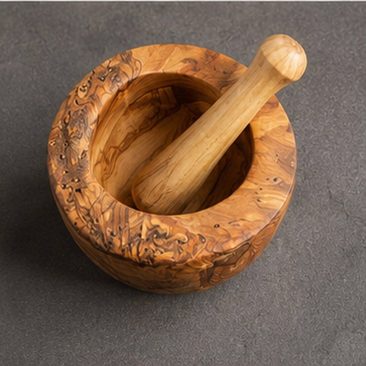 Olive wood mortar and pestle seen from above on a grey stone surface