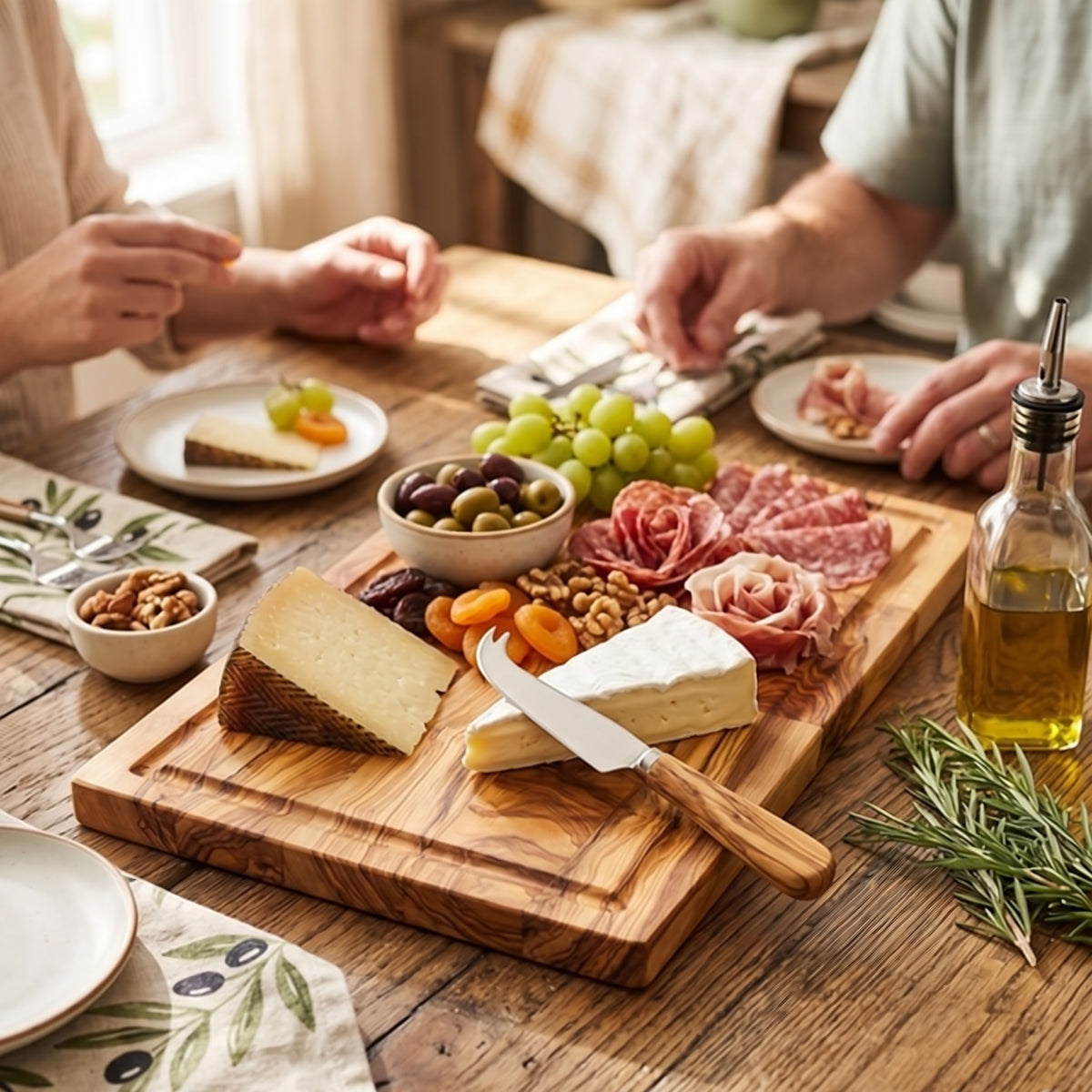 Charcuterie spread on the large olive wood board, set on a dining table for guests