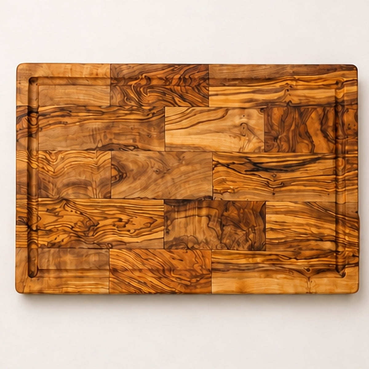Top view of the large olive wood board showing the patchwork grain and the juice groove around the edge