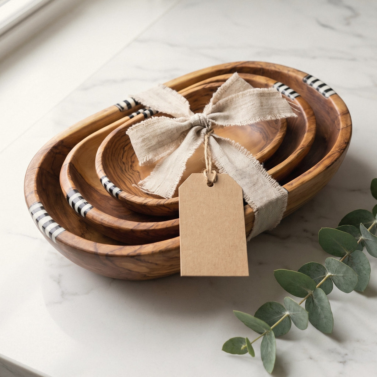 Three nesting olive wood bowls tied with a linen ribbon and a gift tag