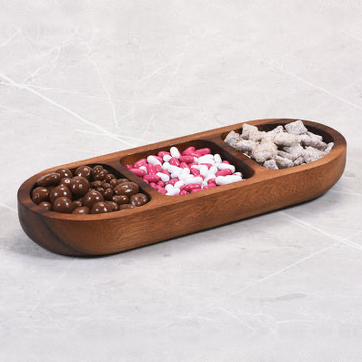 Acacia snack bowl with chocolate candies, mints and snack mix on a marble counter